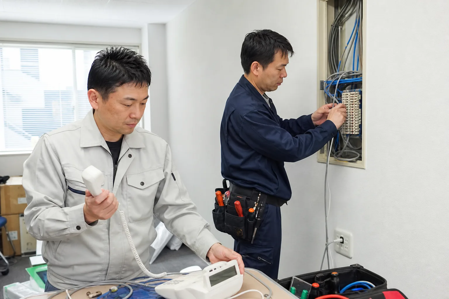 事務所でビジネスフォンの設置作業をするスタッフ