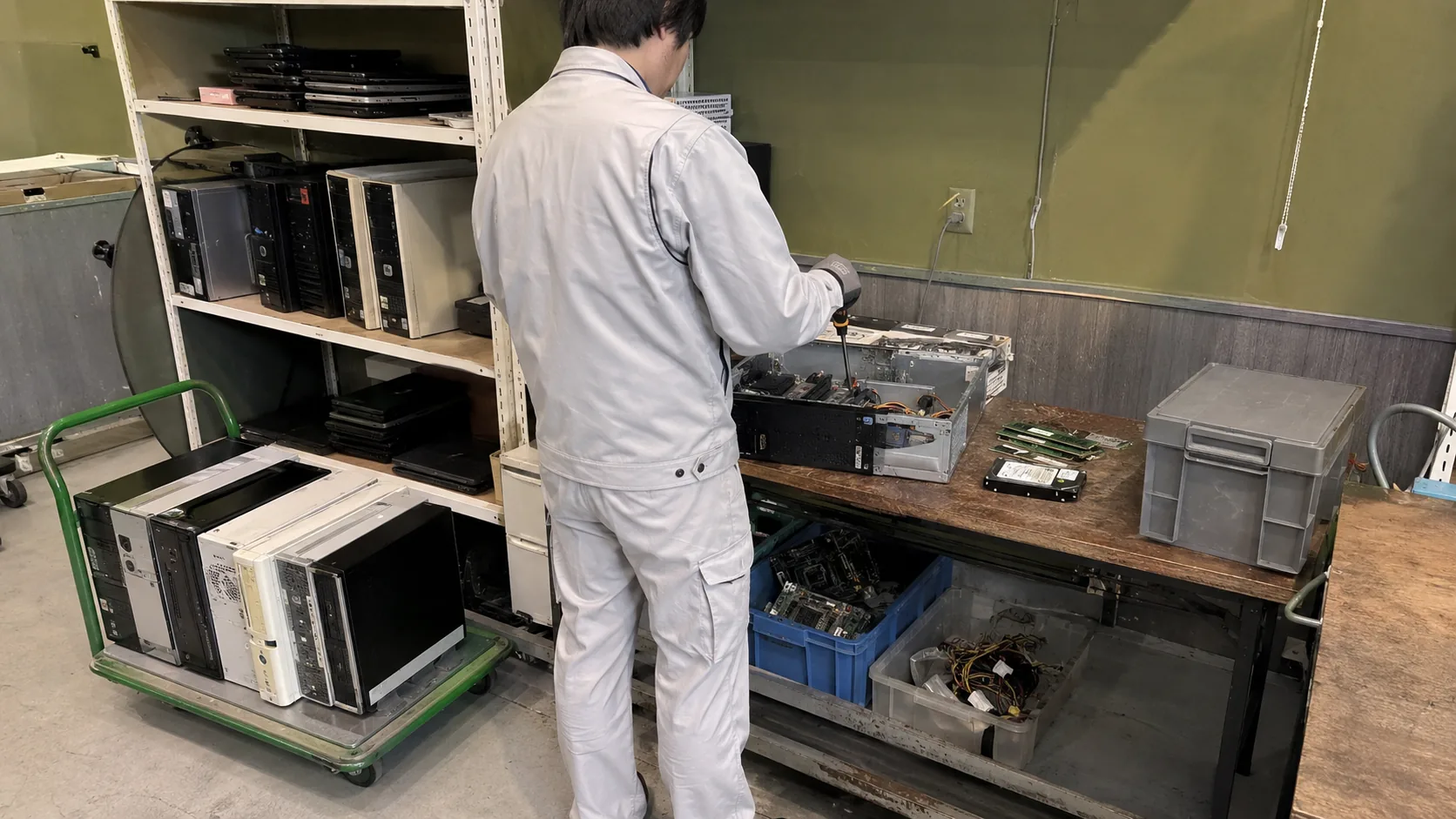 回収したパソコンを分解し、基板・HDD・電源・筐体を部材ごとに分別する作業